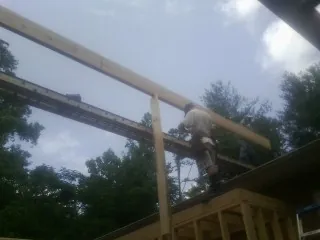 Carpenter setting a ridge beam over a new addition frame — Ice Dam Removal by Roofing Brothers in East Otis