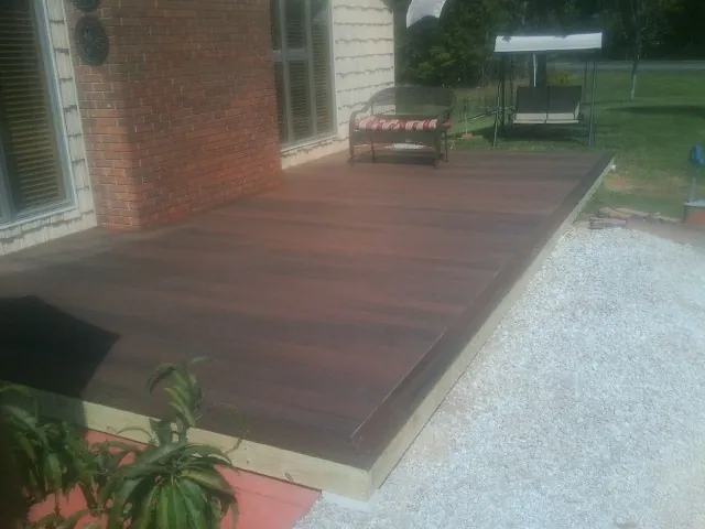 Freshly stained wood deck built against a brick home in East Otis
