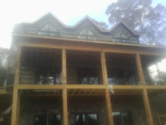 Dormers and porch framing on a large log home under construction — Roof Coating work by our crew in East Otis