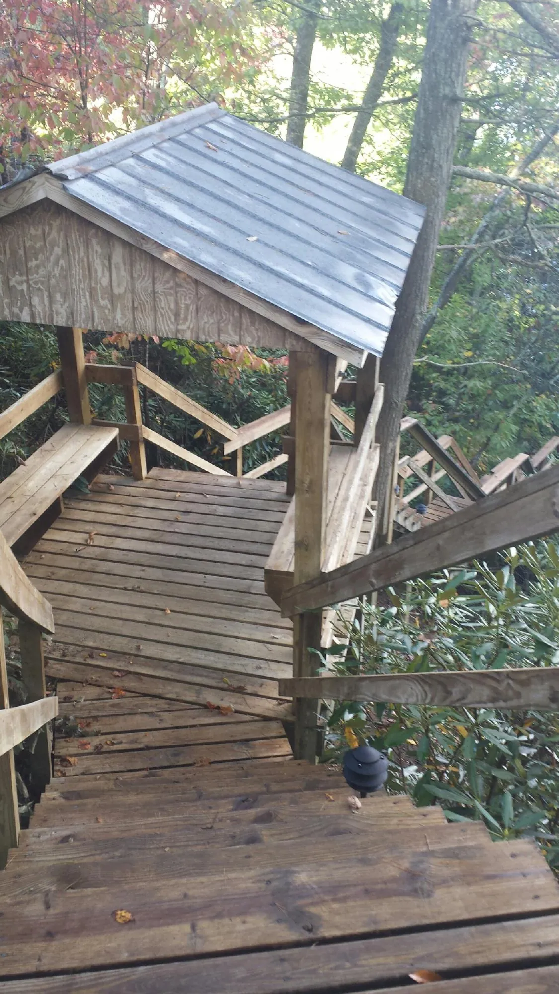 Metal roofed shelter over wooden steps on a wooded walkway — Skylight Repair & Installation work by our crew in East Otis