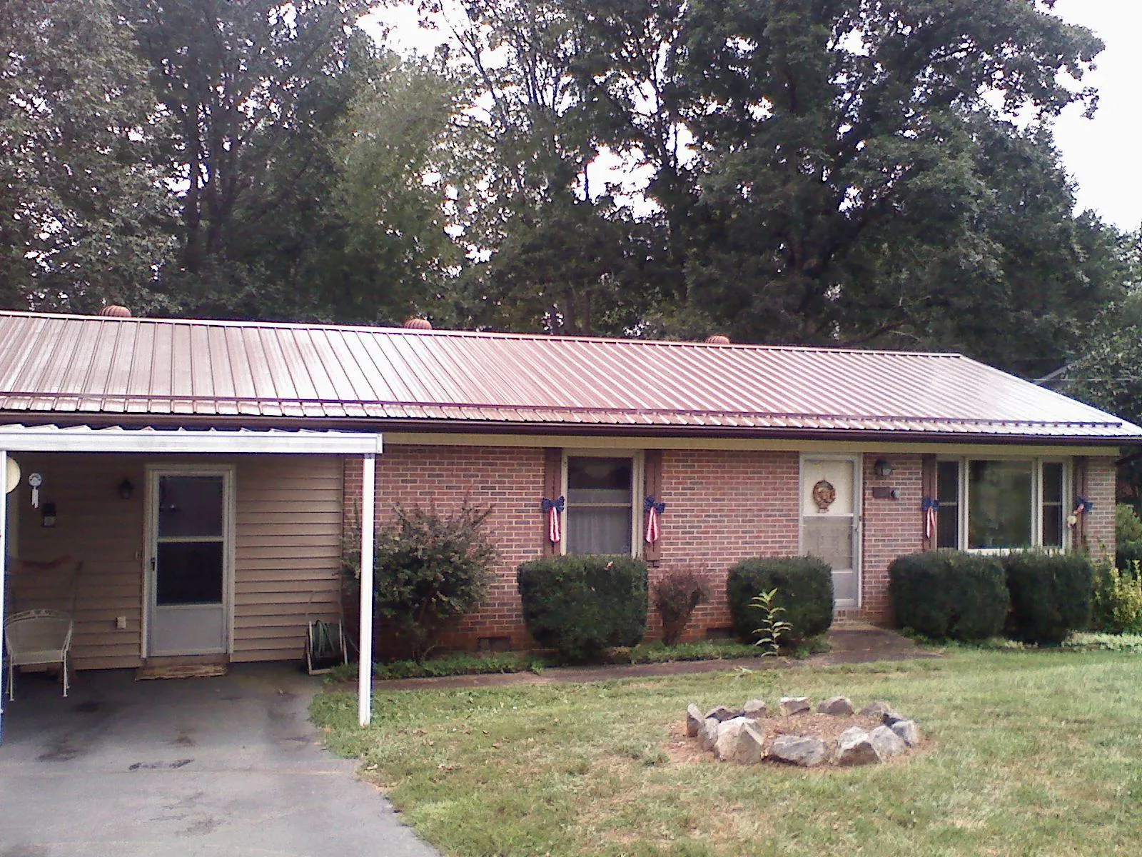 Bronze metal roof and carport on a brick ranch home — Roof Repair work by our crew in East Otis