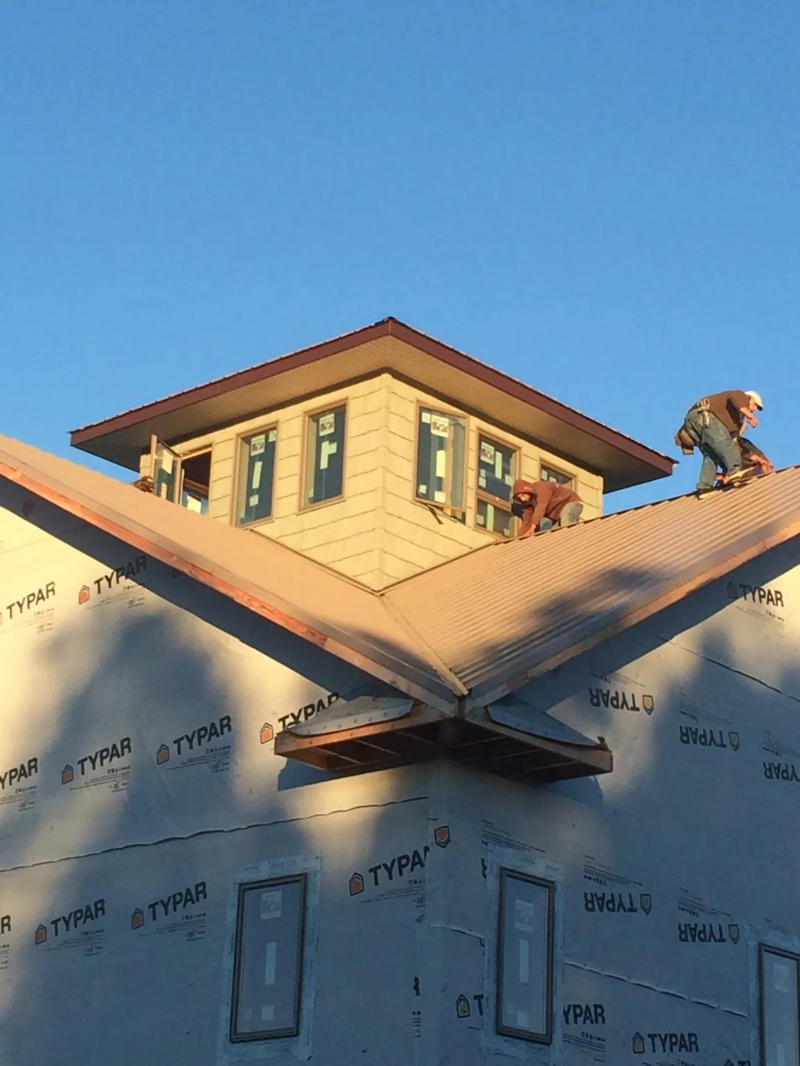 Roofers working around a rooftop cupola on a new metal roof at sunset — Roof Waterproofing in East Otis by Roofing Brothers
